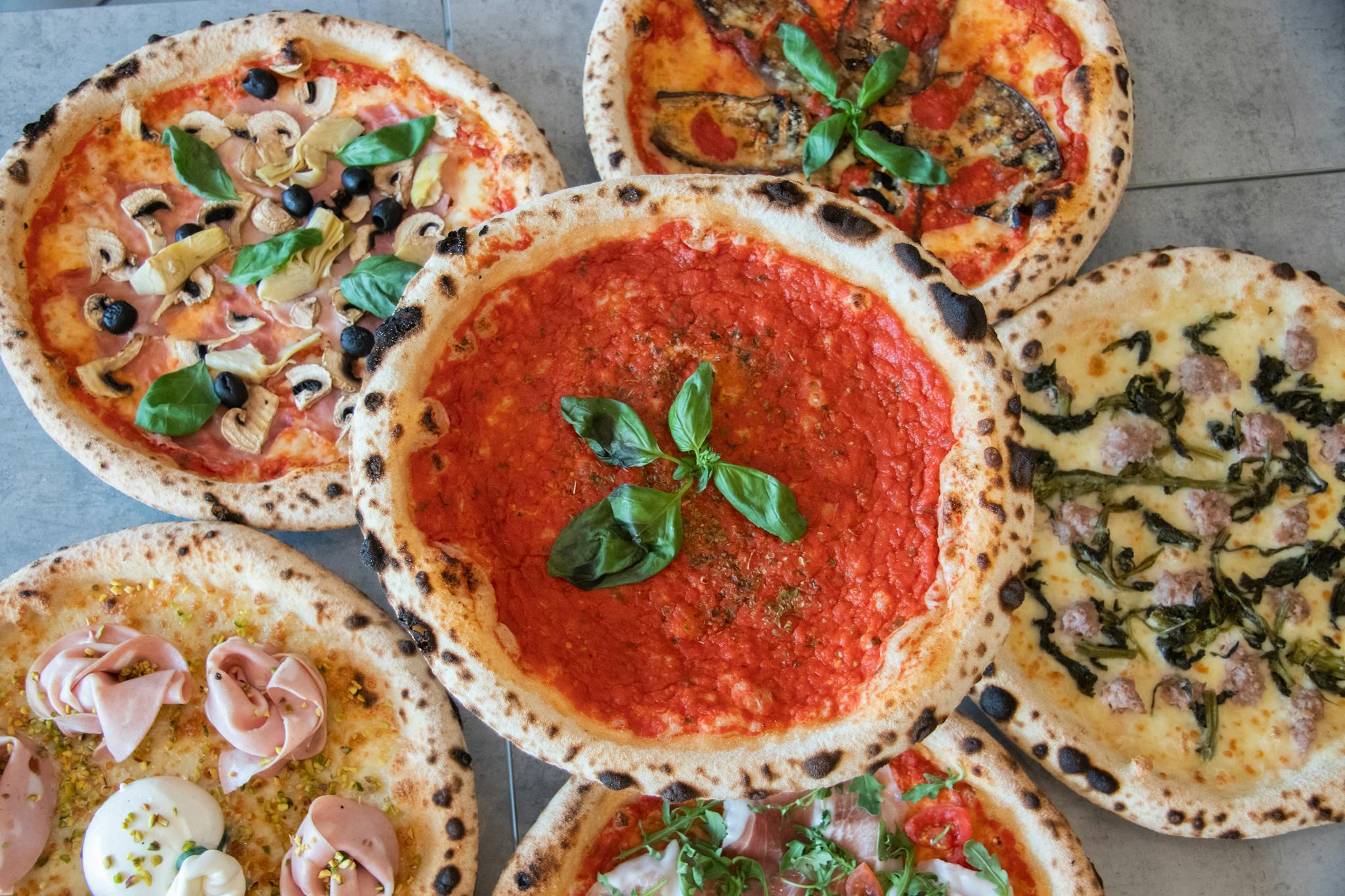 An assortment of fresh Italian pizzas captured in a vibrant top view layout.