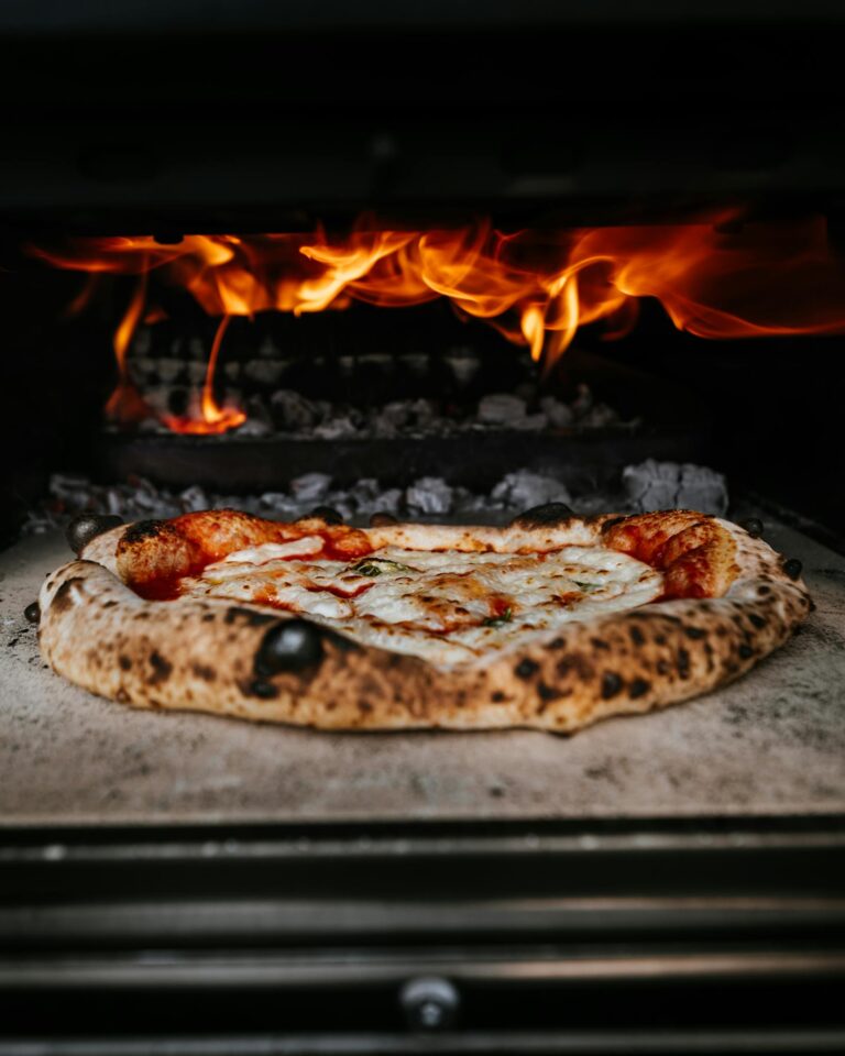 Close-up of authentic pizza cooking in a wood-fired oven with flames.